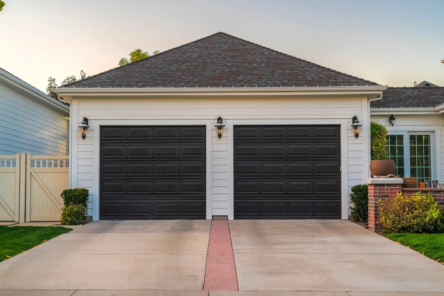 Two-car garage with dark sectional doors and a concrete drive