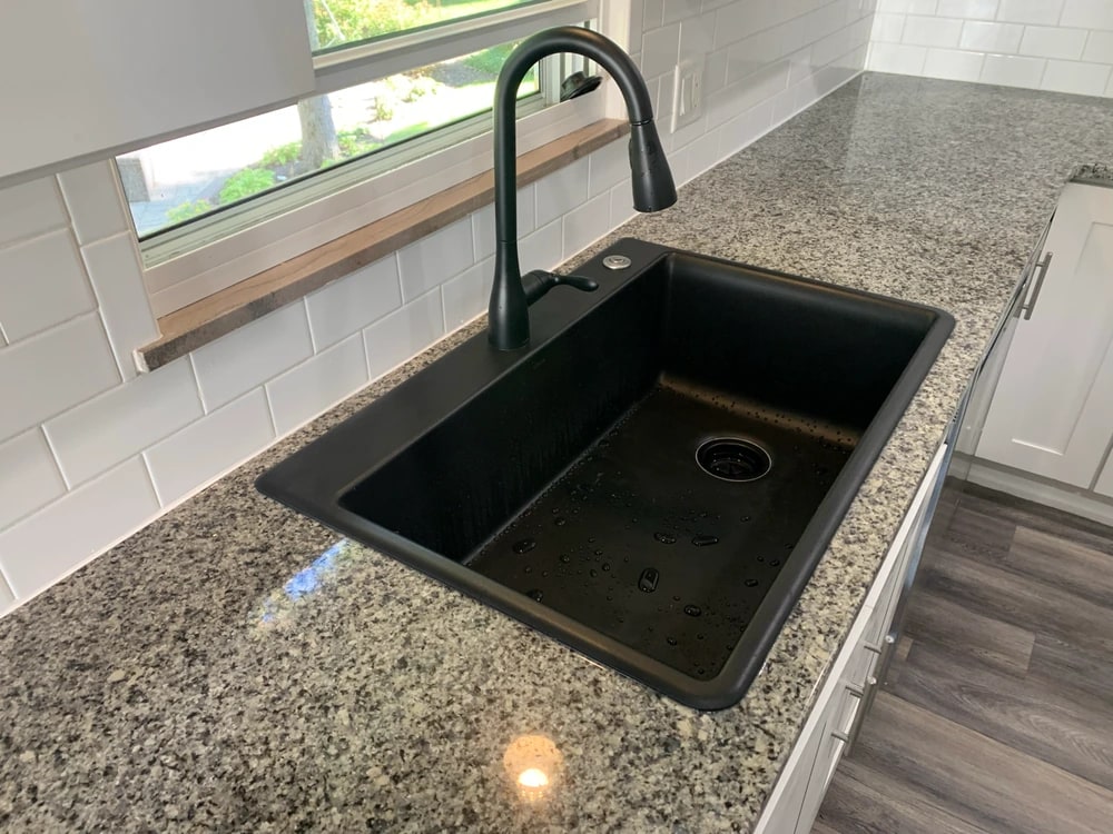Installed dark composite sink with a matching black faucet